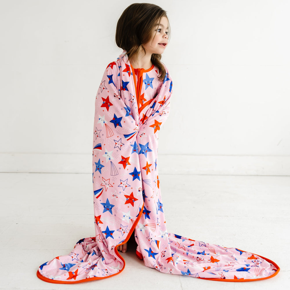 Child wearing a Pink Stars and Stripes Cloud Blanket on her shoulders 