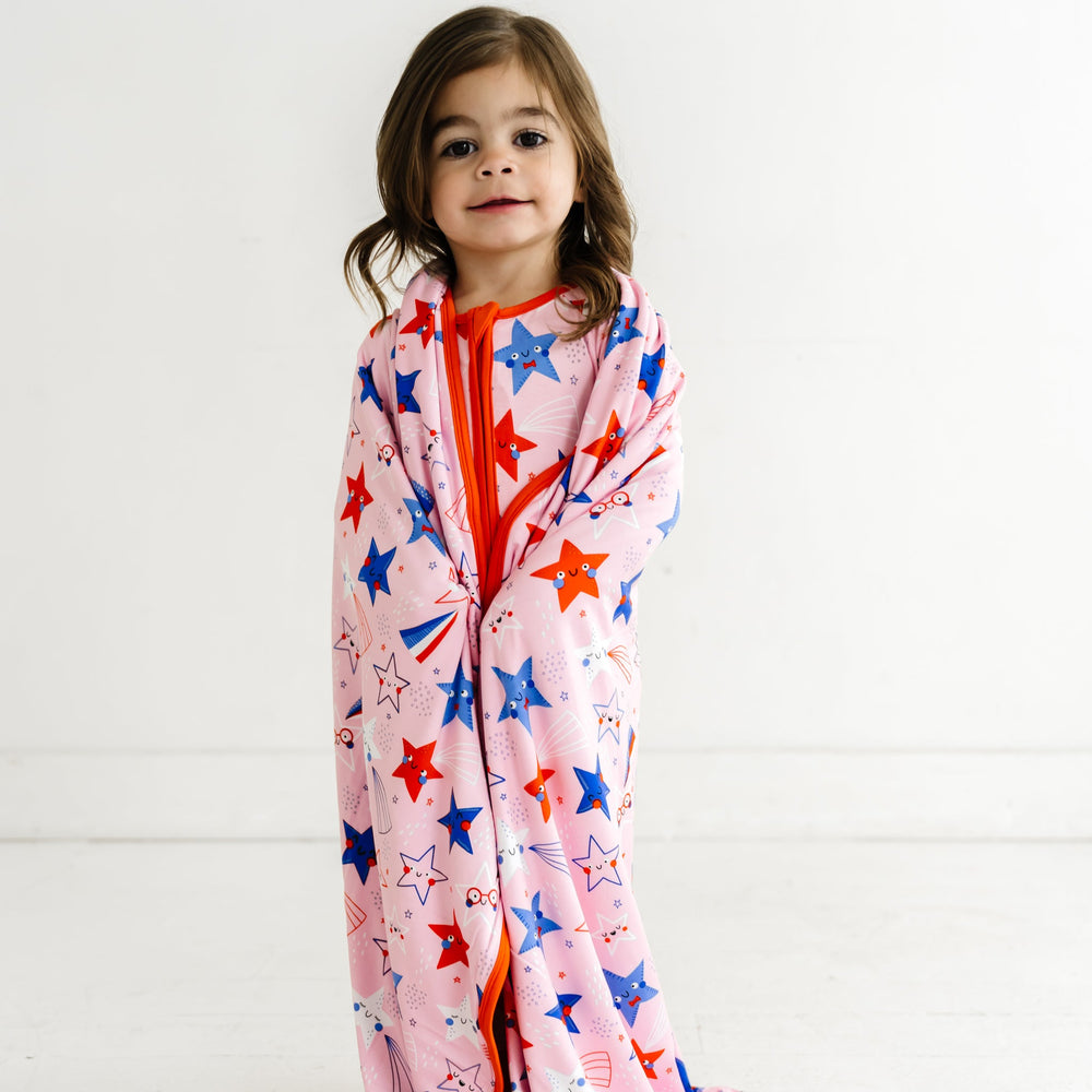 Close up image of a child wearing a Pink Stars and Stripes Cloud Blanket on her shoulders