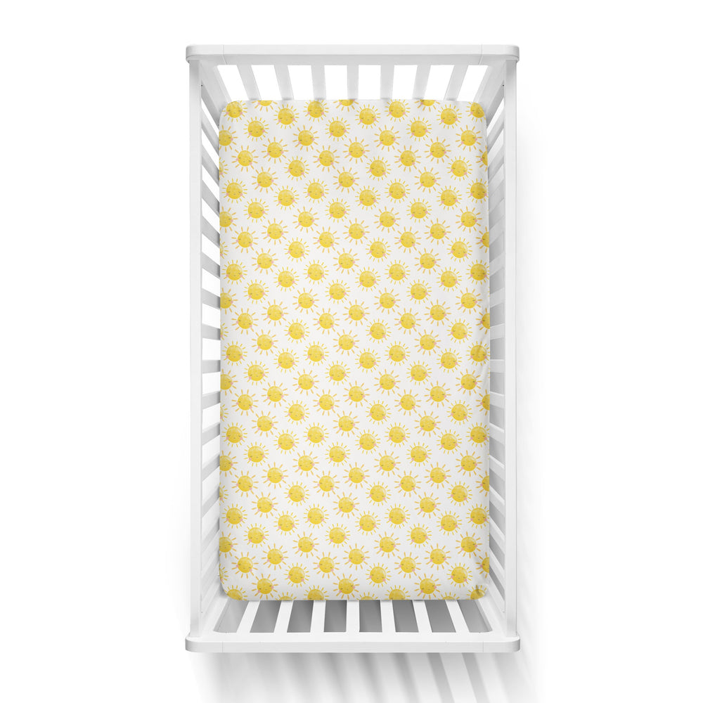 Aerial view of a standard fitted infant crib sheet in Yellow Sunshine print on a white crib