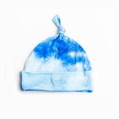 Flat lay photo of infant beanie hat in blue watercolor print. This print features shades of blue watercolors.
