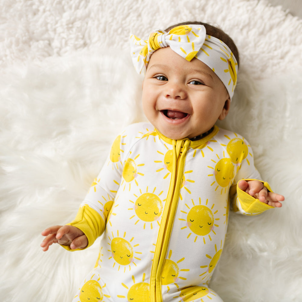 Infant baby wearing zip romper and headband with yellow smiling suns