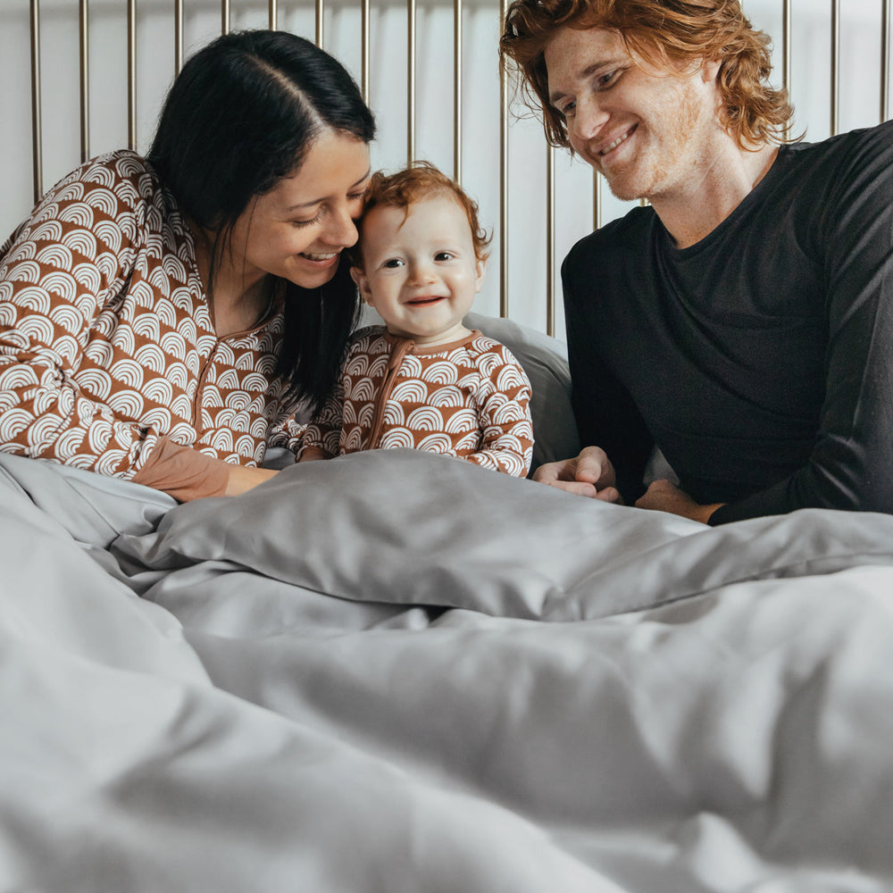 Family wearing Rust Rainbows pajamas in bed cuddling under the Bamboo Duvet Cover in Silver