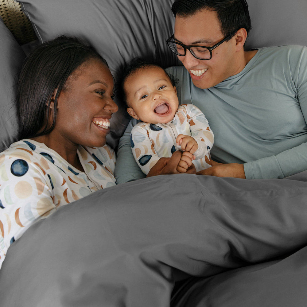 Family wearing Luna Neutral pajamas in bed cuddling under the Bamboo Duvet Cover in Stone