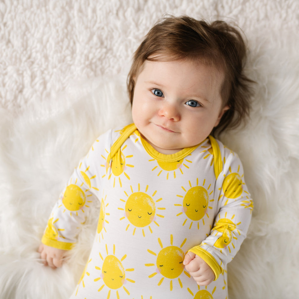 Close up image of infant baby wearing infant gown with printed yellow smiling suns