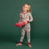 Child posing with a present wearing Holiday Treats two piece pajama set