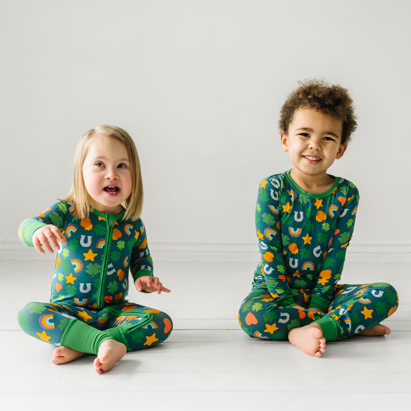 Two children sitting together wearing a Lucky two piece pajama set and matching zippy