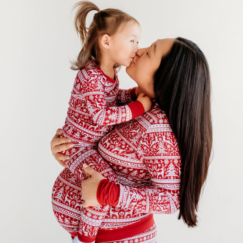 Mother and child posing together wearing matching Reindeer Cheer pajamas. Mom is wearing women's reindeer cheer pants and pajama top. Her daughter is wearing Reindeer Cheer two piece pajama set