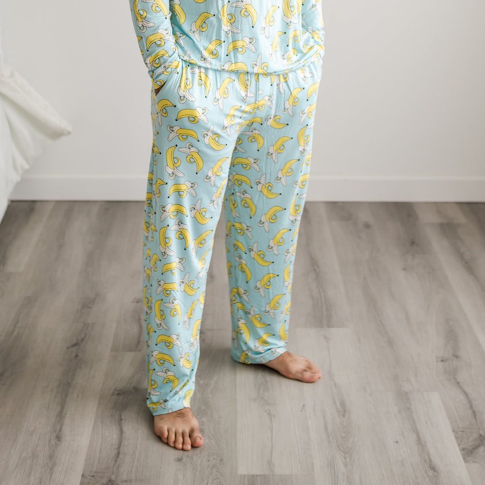 Photo of male model wearing banana printed pajama pants. The pajama pants have a light blue background with pops of yellow coming from the banana print.