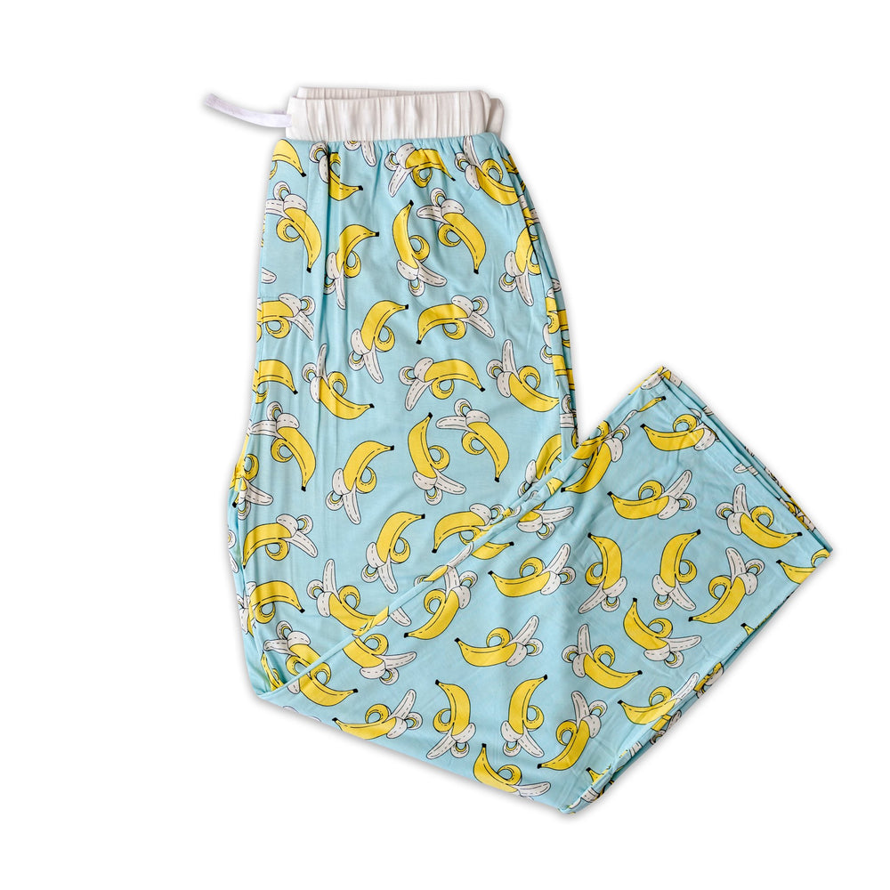 Flat lay photo of men's banana printed pajama pants. The pajama pants have a light blue background with pops of yellow coming from the bananas and white trim accents on the waistband. 