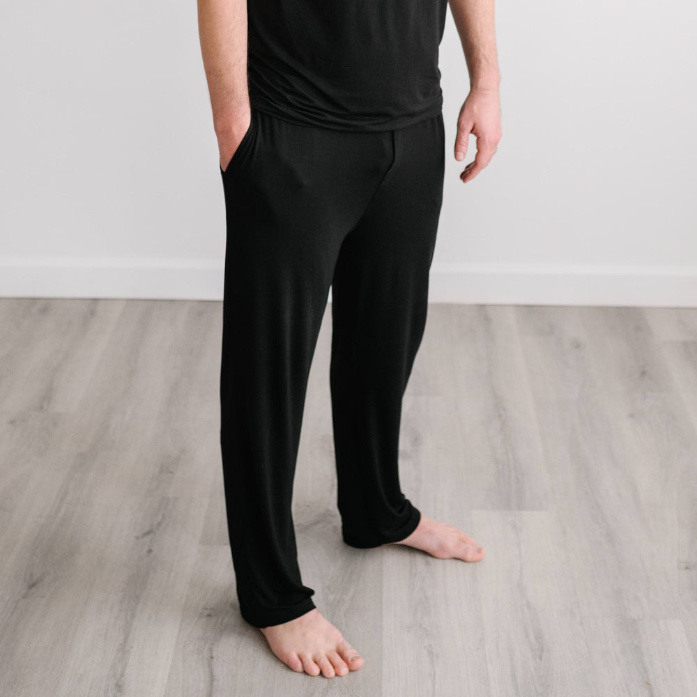 Image of male model wearing solid black pajama pants. 