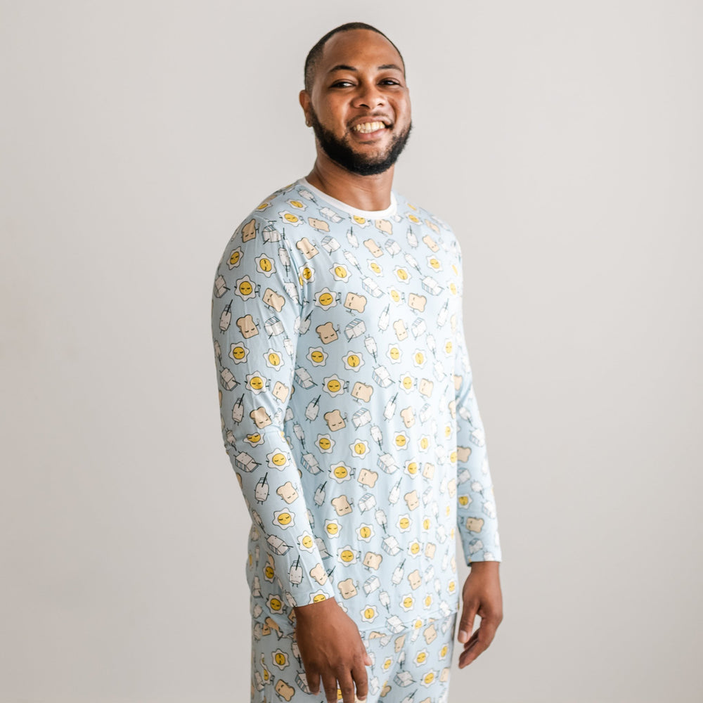 Image of male model wearing long sleeve Blue Breakfast Buddies printed pajama top with white trim accent on the collar. The breakfast foods featured on this print include sunny side up eggs, toast, and milk.