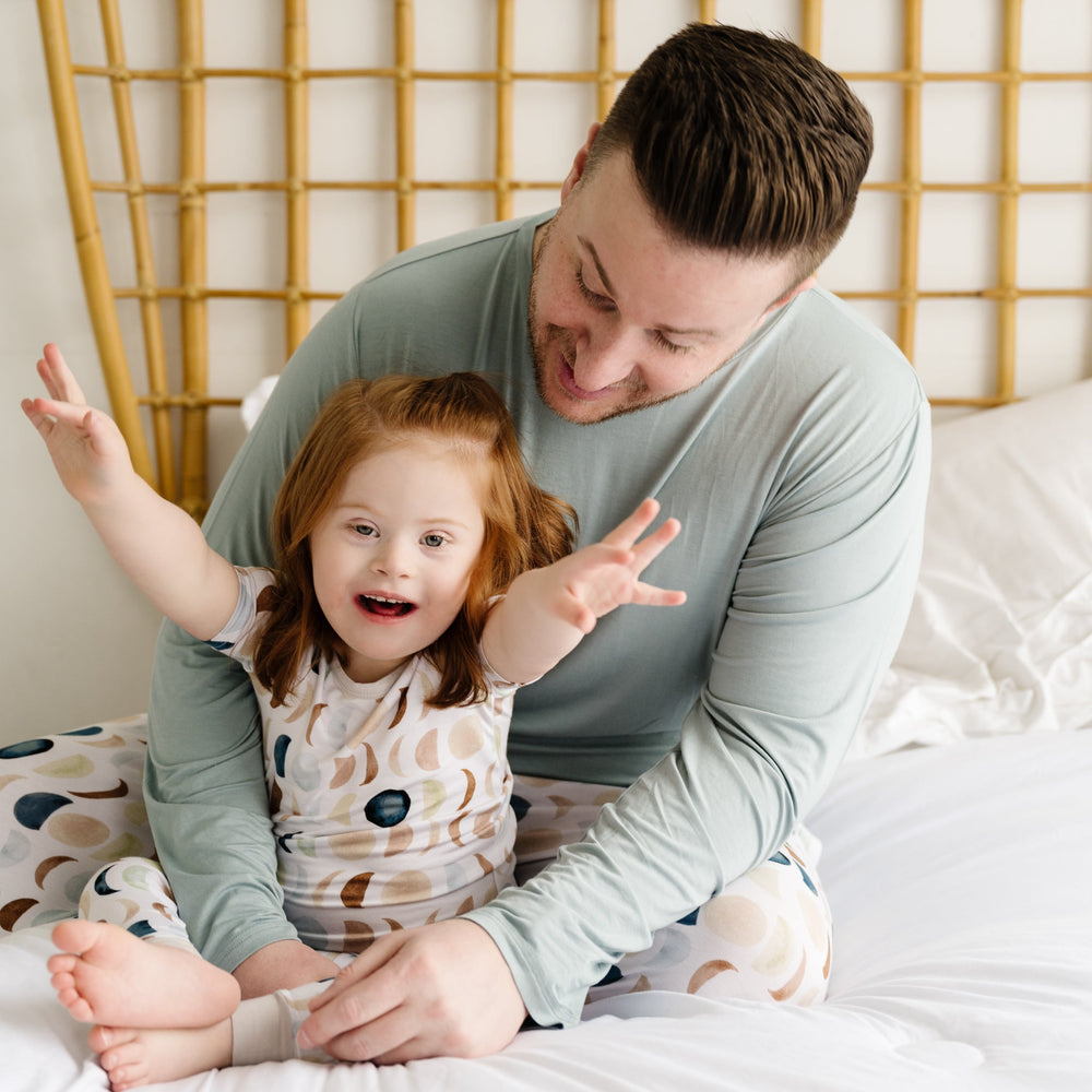 Father and daughter in coordinating matching pajamas in solid color Stormy and Luna Neutral print.