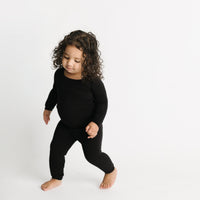 Toddler girl wearing solid black two-piece pajama set. 