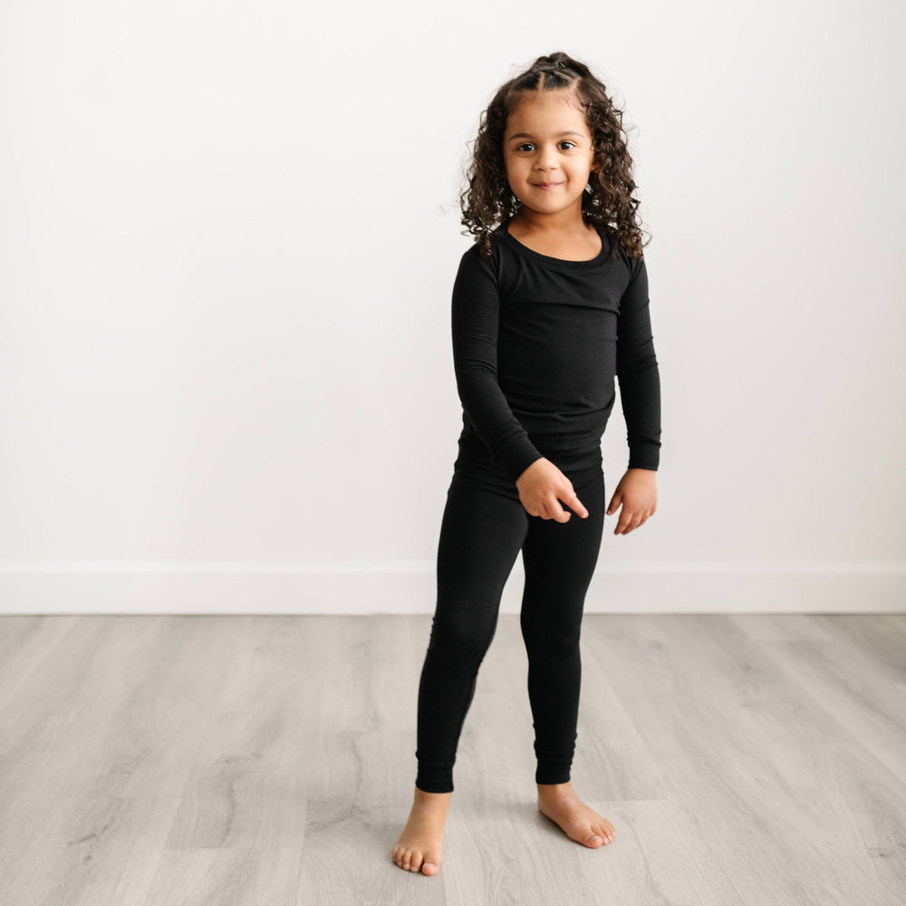 Image of a little girl wearing a solid black two-piece pajama set.