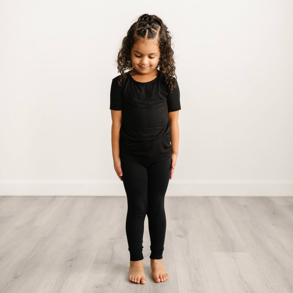 Image of little girl modeling a solid black short sleeve pajama set. 