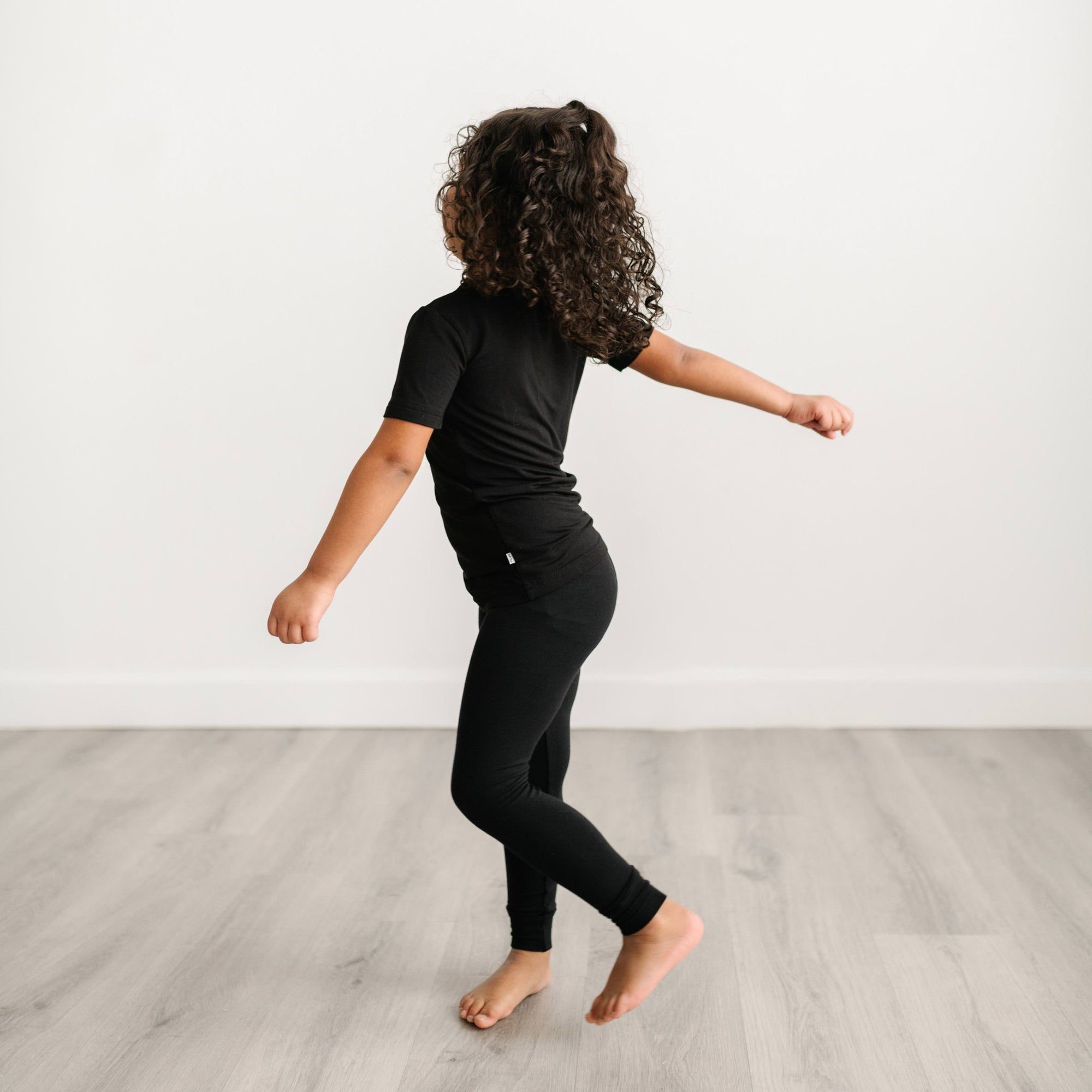 Image of little girl posing in a solid black short sleeve pajama set. 