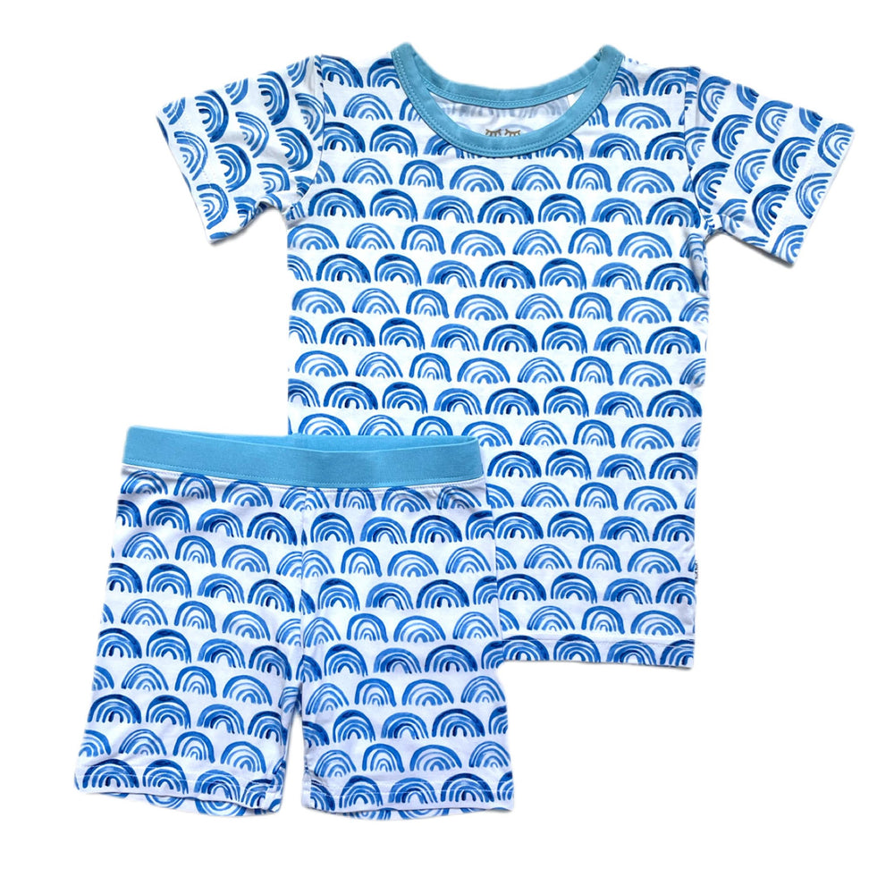 Click to see full screen - Flat lay image of blue rainbow printed short sleeve and shorts pajama set. This print sits on a white background with shades of blue rainbows and sky blue trim details.