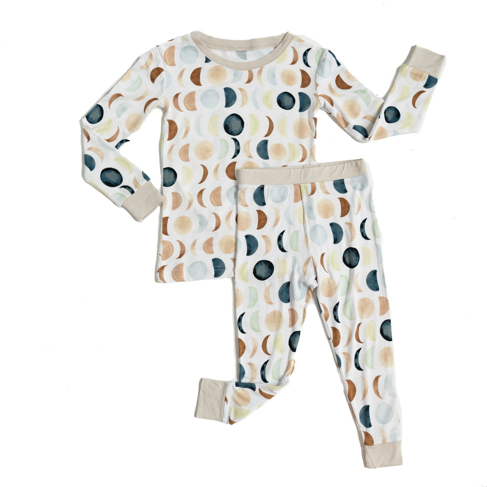 Flat lay image of a two piece long sleeve and pant pajama set in Luna Neutral print. This print features phases of the moon in the sweetest shades of creams, tans, and navy watercolor in an all over repeat pattern.
