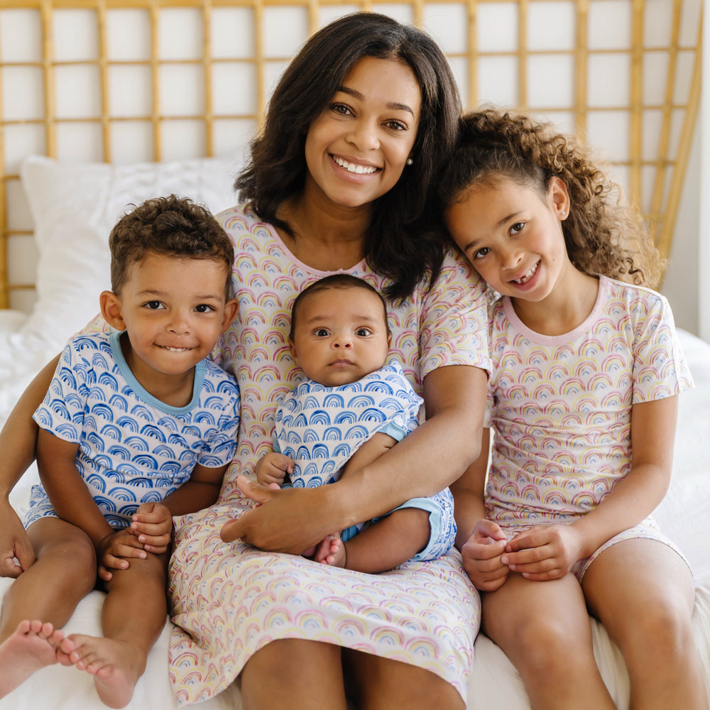 Image of mom and her 3 kids wearing matching rainbow printed pajamas.