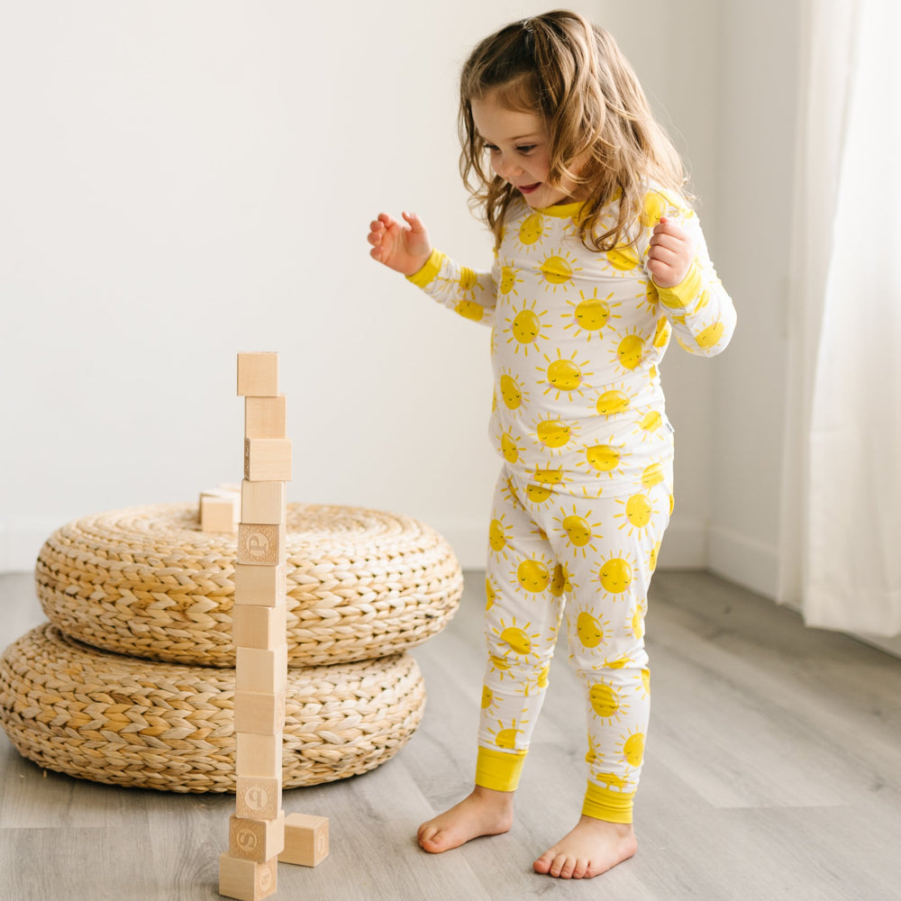 Image of child wearing two-piece pajama set with yellow smiling suns