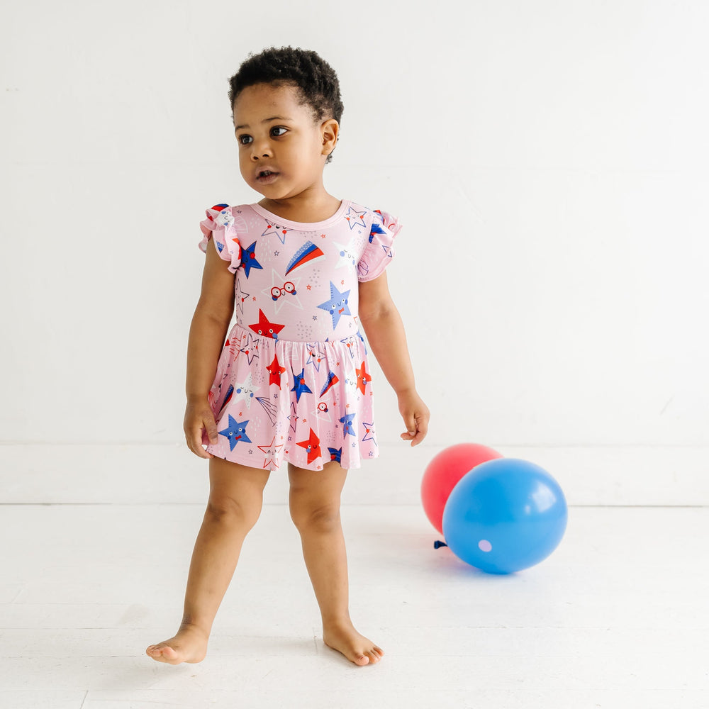 Child posing wearing a Pink Stars and Stripes printed twirl dress with bodysuit
