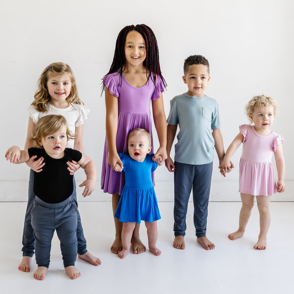 Children in the Play by Little Sleepies collection featuring White Short Sleeve Flutter Tee, Black Short Sleeve Bodysuit, Charcoal Joggers, Orchid Twirl Dress, Cobalt Twirl Dress with Bodysuit, Stormy Short Sleeve Pocket Tee, Charcoal Leggings, Blush Pink Twirl Dress with Bodysuit.