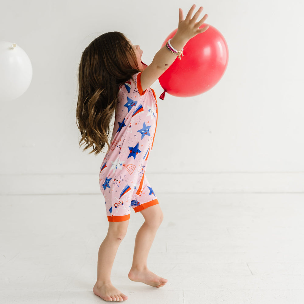 Child playing with a balloon wearing a Pink Stars and Stripes printed shorty romper