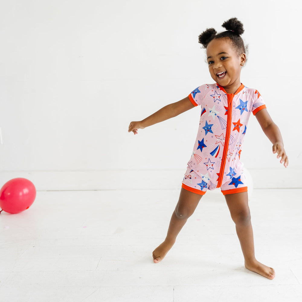 Child playing with a balloon wearing a Pink Stars and Stripes printed shorty romper