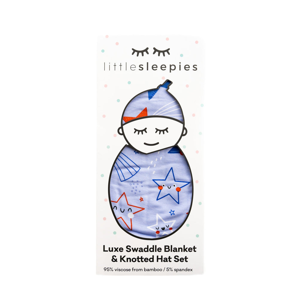 Flat lay image of Blue Stars and Stripes printed swaddle and hat set packaged in Little Sleepies peek-a-boo packaging 