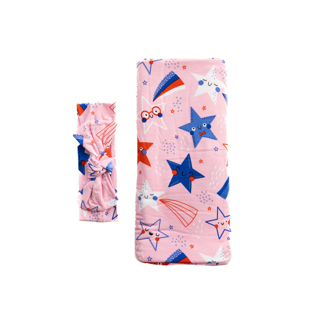 Flat lay image of Pink Stars and Stripes printed swaddle and headband set