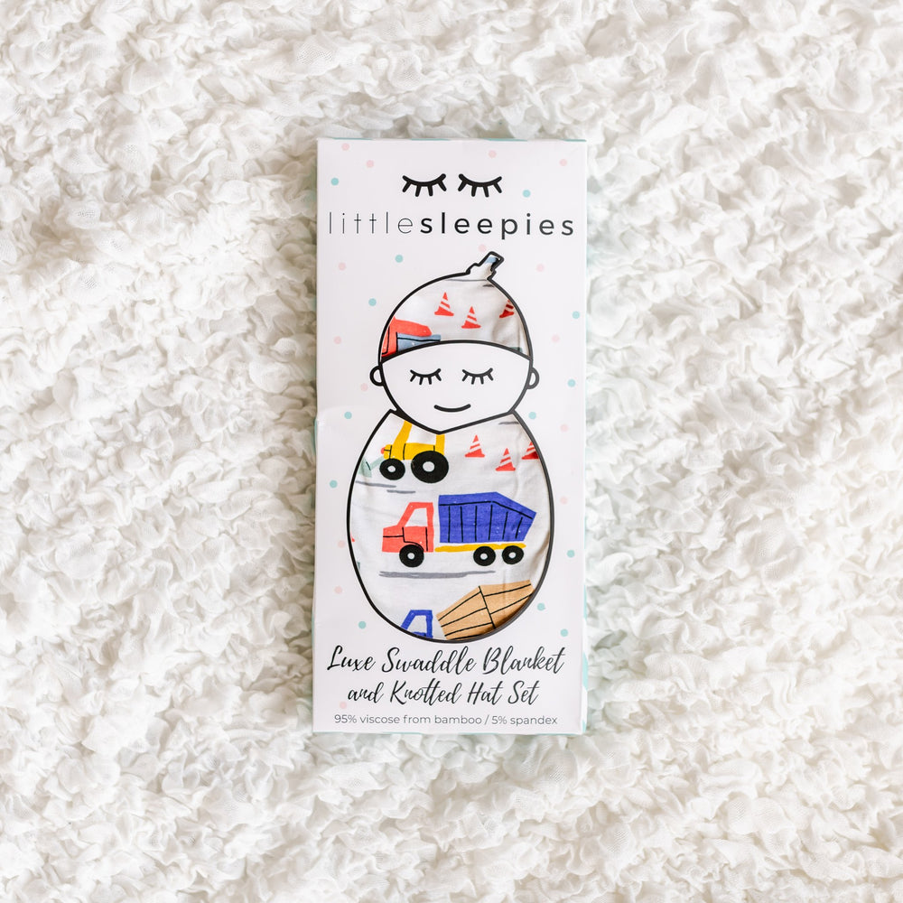 Image of construction printed swaddle and hat set in Little Sleepies packaging.