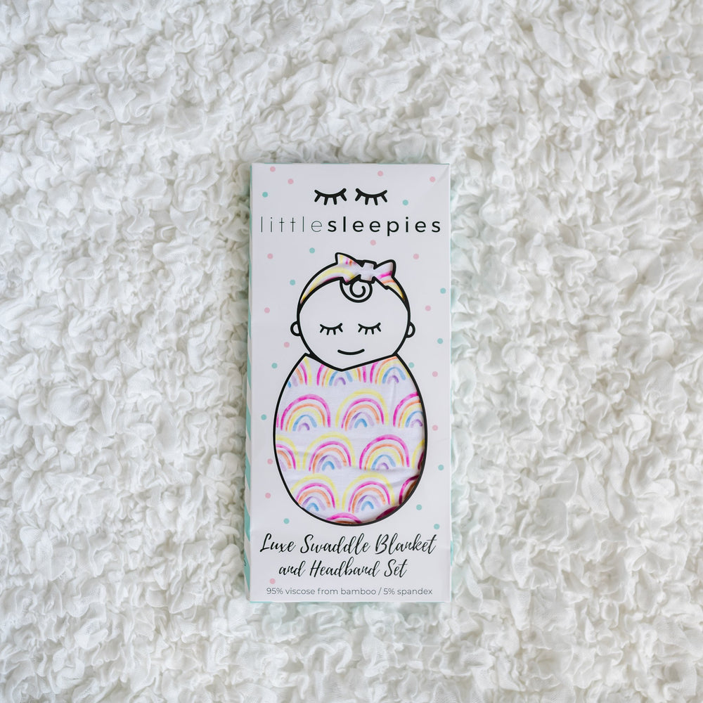 Image of rainbow printed swaddle and headband set in Little Sleepies packaging. 
