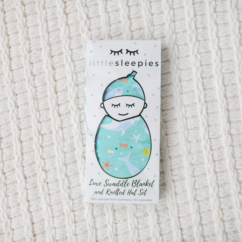 Image of shark printed swaddle and hat set in Little Sleepies packaging. 