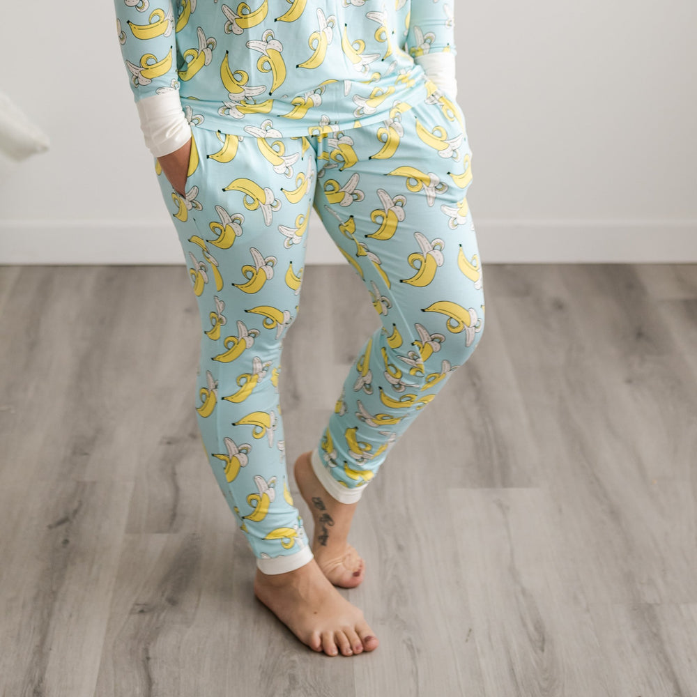 Female model wearing banana printed pajama pants. This print features a light blue background with white trim accents and pops of yellow coming from the bananas. 