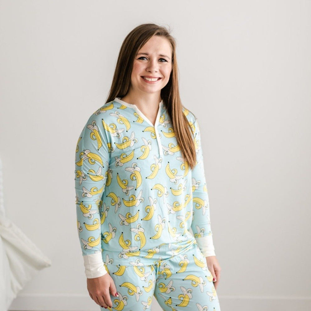 Female model wearing banana printed pajama top. This long sleeve top features a light blue background and pops of yellow with white trim accents on the collar and sleeve cuffs. 