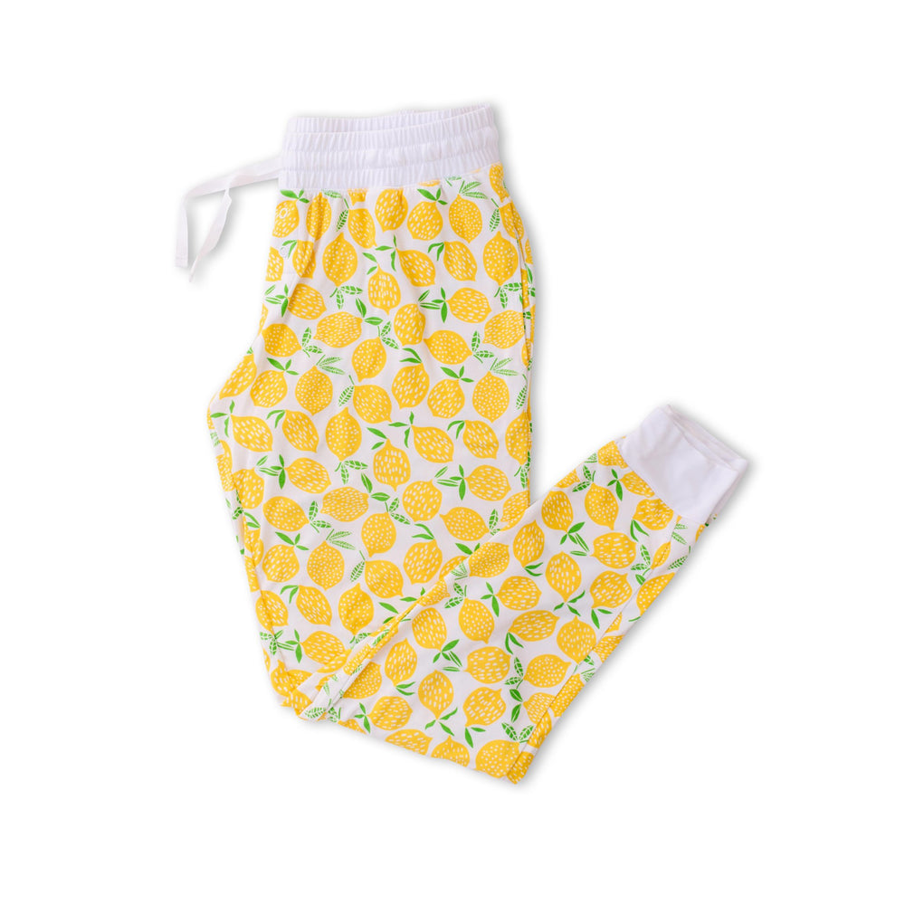 Flat lay image of women's pajama pants in Lemons print. This print features vibrant pops of yellow fruit with green accents that sit upon a white background with white trim.