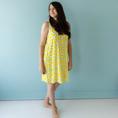 Image of female model shown wearing our luxuriously soft, Lemons printed sleeveless nightgown. This Lemons print is sure to brighten your day! This signature print features vibrant pops of yellow fruit with green accents that sit upon a white background with white trim. 