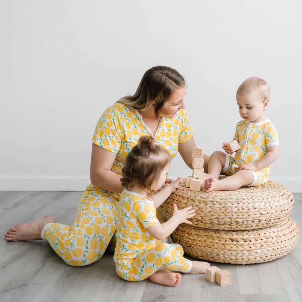 Woman with her children playing with wooden blocks wearing matching pajama sets in Lemons print