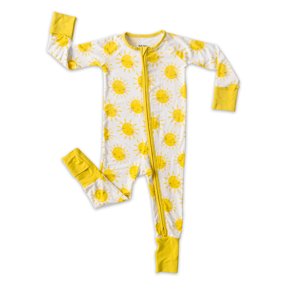 Flat lay image of zip up romper in Sunshine print. This print features yellow smiling suns that sit on a white background with yellow trim.