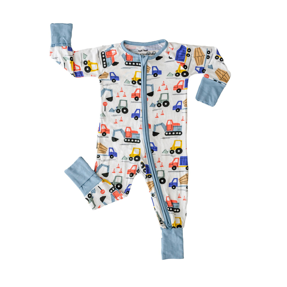 Flat lay photo of zip up romper in construction print. This print features utility trucks and tractors on a white background with sky blue trim accents.