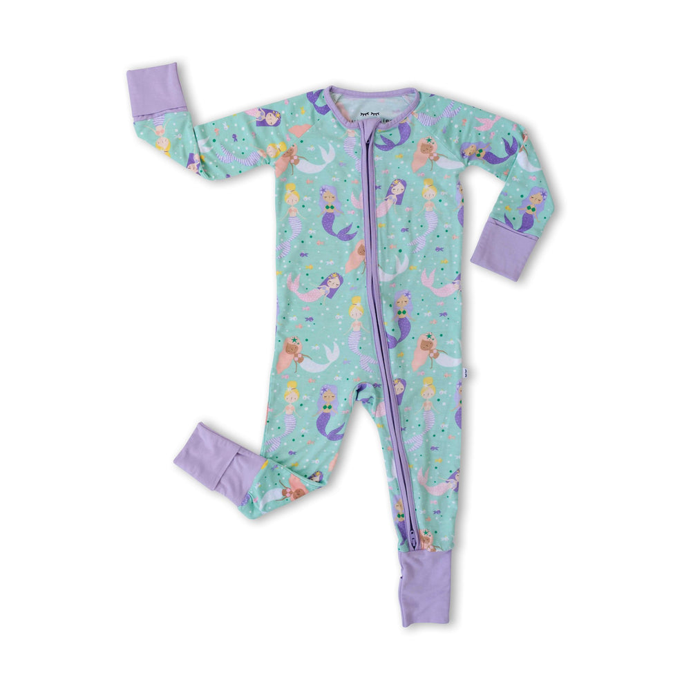 Flat lay image of zip up romper in mermaid print. This print includes multi-colored mermaids and fish that are featured on an aqua background with a purple trim.
