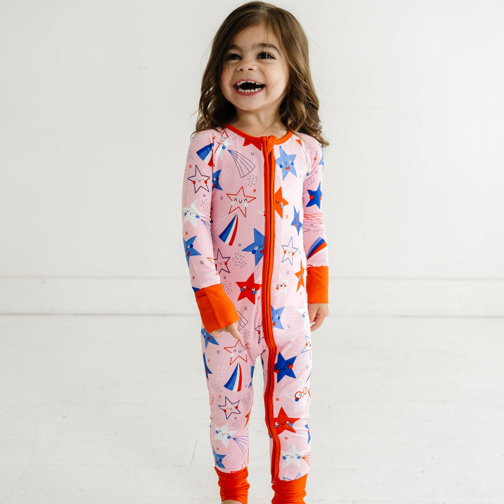 Child posing wearing a Pink Stars and Stripes printed zippy