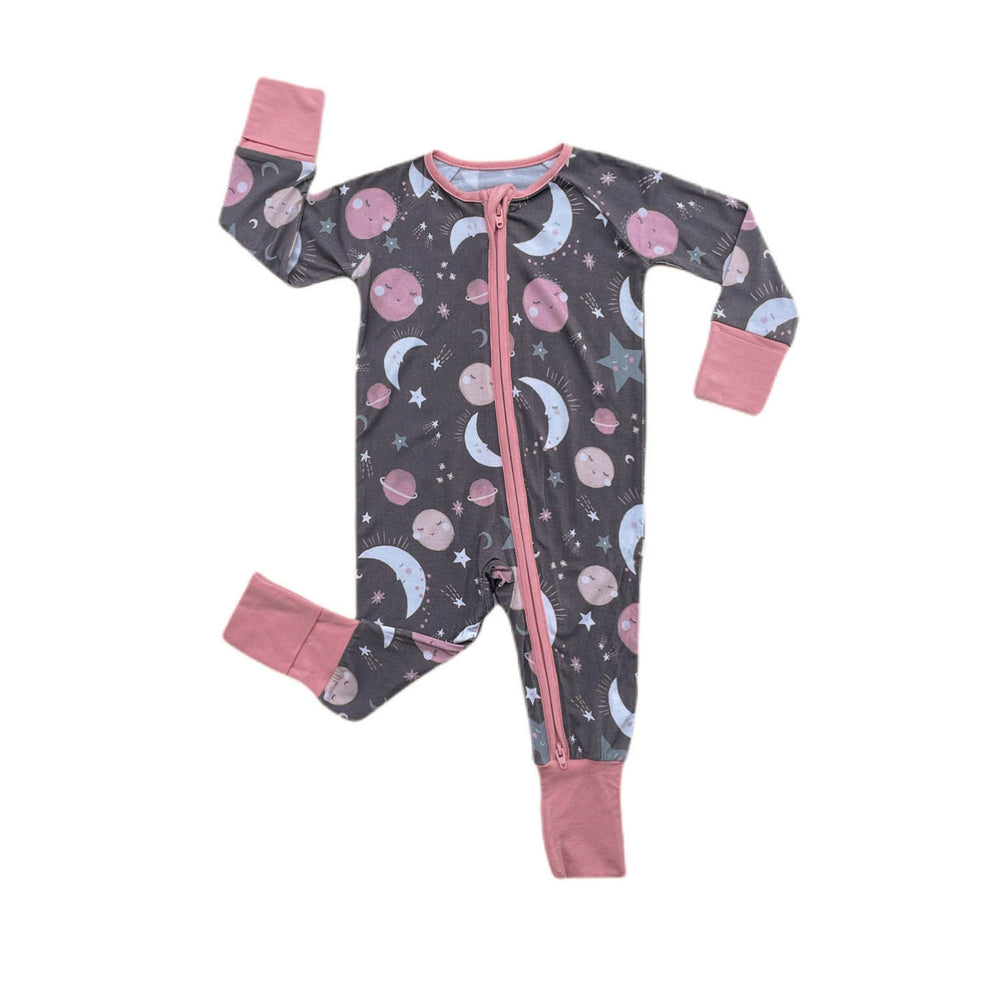 Flat lay image of long sleeve zip up romper in pink to the moon and back print. This print features pink and gray moons, stars, and planets on a charcoal background with a matching pink trim. 