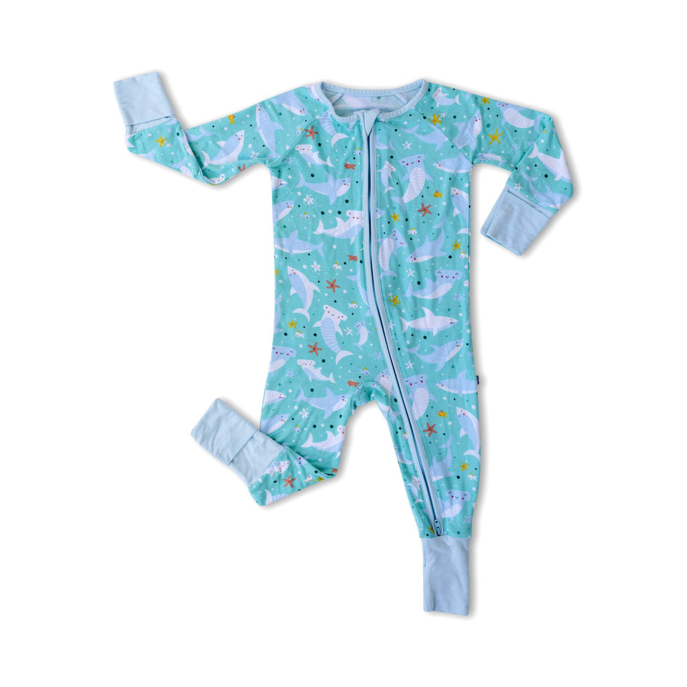 Flat lay image of zip up romper in sharks print. This print includes hammerhead and great white sharks, featured on an aqua background with a light blue trim. 